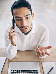 Image showing Confused, business man and phone call with laptop, conversation and in office. Asian male, cellphone and talking for startup company, upset for deal and communication problem, smartphone and top view