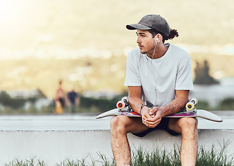 Image showing Young man, skateboard and relax outdoor, thinking or chill being casual, trendy and earphones. Mockup, male skater or idea for break, calm or cool look being edgy, content or hipster on weekend style