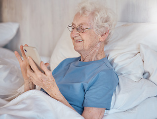 Image showing Elderly woman, retirement home and smartphone in bed of nursing home for medical care to relax to support healthcare. Senior with happy smile, in hospital bed and rehabilitation for physical health