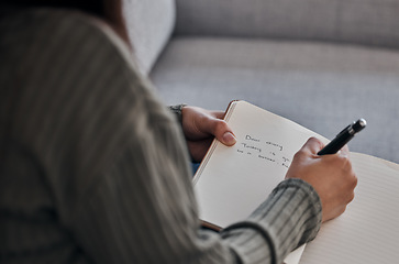 Image showing Hand, book and woman writing in journal on a sofa for planning, brainstorm and feeling log closeup in a living room. Notebook, diary and girl with mental health problem write note on emotions in home