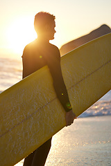 Image showing Beach, surfer and man with a surfboard at sunset thinking of of fitness training, workout or water sport exercise outdoors. Silhouette, freedom and healthy athlete on a holiday vacation for surfing