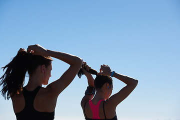 Image showing Fitness women, silhouette and blue sky background of runner tying hair together after outdoor run, cardio exercise and wellness health. Healthy running girls, sports athlete and friends morning run