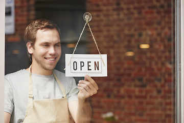 Image showing Open sign, startup and small business owner in coffee shop with pride and happiness to welcome people at front door of restaurant. Happy entrepreneur ready for service at cafe or retail store