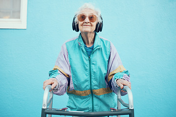 Image showing City, fashion and senior woman with headphones listening to music, audio and radio on blue background wall. Freedom, style and elderly female with modern, urban and trendy clothes with walker in town