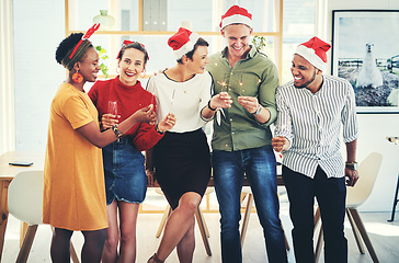 Image showing Company Christmas party, staff and holiday celebration, corporate diversity and fun together at the office. Team with light sparklers, champagne and drinking to celebrate, group and happiness.