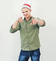 Image showing Christmas, portrait and festive with a model man in studio on a gray background wearing a hat for the holidays. Tradition, celebration and seasons greetings with a male in a santa cap while pointing