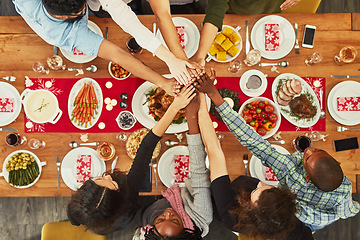 Image showing Christmas, high five and food with a group of friends sitting around a dinner table together for celebration. Thanksgiving, hands and meal with a team enjoying a lunch on a wooden surface from above