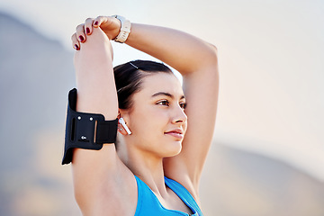 Image showing Young woman, stretching and with arm band for exercise, training and fitness for health and relax outdoor. Healthy female, girl athlete and podcast for balance, calm or wellness for cardio or workout