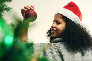 Image showing Christmas, decoration and girl with smile for tree, holiday and celebration in a house. Happy, festive and child decorating the Christmas tree to celebrate the festive season in a house for fun