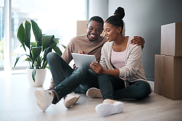 Image showing African couple, real estate and tablet for new house interior shopping, property or relax on floor with boxes. Realtor, happy online communication and homeowners moving or packing apartment together