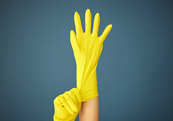 Image showing Cleaning, yellow rubber glove and hand on studio background for cleaner, hygiene and spring cleaning mockup on blue background. Hand of woman in uniform for housekeeping and cleaning service mock up