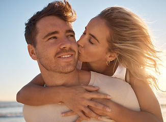 Image showing Love, summer and couple kiss at a beach at sunset, hug and romantic travel, holiday and fun against blue sky background. Romance, bond and woman with man at the sea, embrace and enjoy trip in Mexico