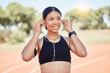 Image showing Fitness, exercise and black woman listening to music with earphones for running motivation while outdoor at stadium for marathon or race training. Smile of athlete happy before exercise or run