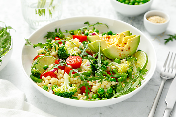 Image showing Couscous salad with broccoli, green peas, tomatoes, avocado and fresh arugula. Healthy natural plant based vegetarian food for lunch, israeli cuisine
