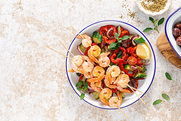 Image showing Shrimp kebab roasted on skewers and fresh vegetable salad, top view