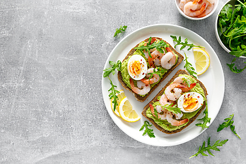 Image showing Toast with shrimps, avocado guacamole, arugula and boiled egg, top view