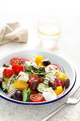 Image showing Greek salad. Vegetable salad with feta cheese, tomato, olives, cucumber, red onion and olive oil. Healthy vegetarian mediterranean diet food