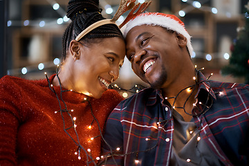 Image showing Couple, christmas celebration and festive holiday, lights and happy smile, hat and love together with home decoration. Black man, woman or happiness for xmas in house, celebrate or enjoy with partner