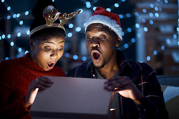 Image showing Black couple, box and christmas gift open in surprise, wow and shock by magic light and looking excited. Night, couple and gift box fantasy, omg and amazed while sharing festive holiday in a home