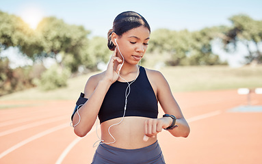 Image showing Music, earphones and runner woman pulse check on workout, training and athlete break. Wellness, fitness and running girl pause at stadium track for performance analysis on smartwatch app.