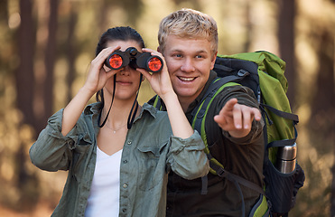 Image showing Couple, binoculars and pointing while hiking in nature, travel or outdoors vacation, holiday or trip. Freedom, man and woman on adventure, sightseeing or trekking and looking with field glasses.