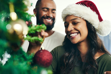 Image showing Christmas, tree and smile with a black couple decorating in the home together for the festive season. Love, celebration and holidays with a happy man and woman in a santa hat while bonding in a house