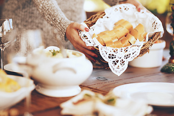 Image showing Woman, bread basket and food at dinner table in home, house and dining room for family lunch, meal and hosting social gathering together. Closeup sliced baguette for party, celebration and eating