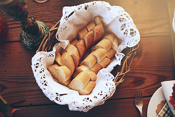 Image showing Bread, food and basket with a starter serving on a wooden dinner table in a home for a celebration event. Party, lunch and mutrition with a baguette on a surface for eating, dining or a meal