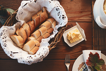 Image showing Table, bread and butter for dinner, lunch or festive celebration for thanksgiving, christmas or birthday. Dining table, food and decoration for party in home, house or restaurant with basket for meal