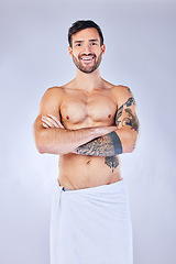 Image showing Shower, towel and hygiene with a topless man in studio on a gray background for wellness or body care. Portrait, cleaning and tattoo with a handsome young male standing arms crossed in a bathroom