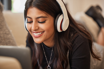 Image showing Laptop, music and headphones with an indian woman listening to audio in the living of her home. Podcast, streaming and subscription service with a young female typing on her computer on the sofa