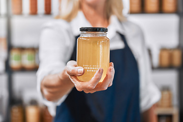 Image showing Glass, honey and hand of woman small business owner offering raw, organic and healthy product in her store. Local business, businesswoman and honey jar in a market, eco friendly and sustainable