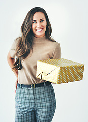 Image showing Christmas, birthday or holiday with woman giving gift or present to celebrate and surprise on a studio background. Portrait of a female with a smile, happiness and kindness holding a mockup gift box