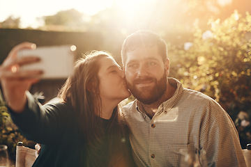 Image showing Happy couple, selfie on a phone with a kiss for love, care and support while outdoor in garden with lens flare for summer. Man and woman together with smartphone for social media profile picture