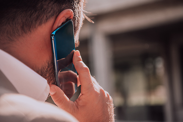 Image showing A businessman using his smartphone outdoors, showcasing the seamless integration of technology and mobility in modern professional life.