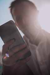 Image showing A businessman using his smartphone outdoors, showcasing the seamless integration of technology and mobility in modern professional life.