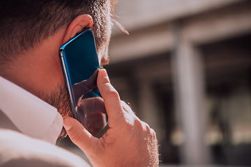 Image showing A businessman using his smartphone outdoors, showcasing the seamless integration of technology and mobility in modern professional life.