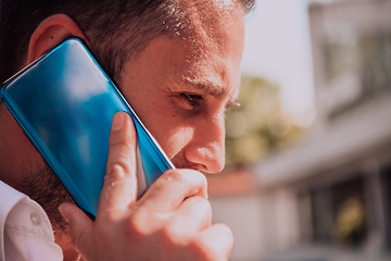 Image showing A businessman using his smartphone outdoors, showcasing the seamless integration of technology and mobility in modern professional life.