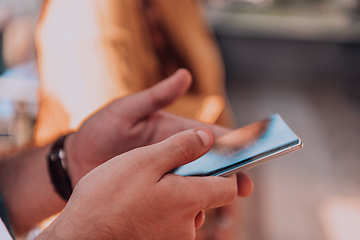 Image showing Closeup photo of businessman hand utilizes his smartphone outdoors, showcasing the seamless integration of technology and mobility in modern professional life.