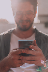 Image showing A young man utilizes his smartphone outdoors, showcasing the seamless integration of technology and mobility in modern professional life.