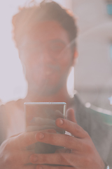 Image showing A young man utilizes his smartphone outdoors, showcasing the seamless integration of technology and mobility in modern professional life.