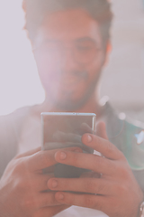 Image showing A young man utilizes his smartphone outdoors, showcasing the seamless integration of technology and mobility in modern professional life.