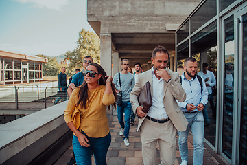 Image showing A diverse group of businessmen and colleagues walking together by their workplace, showcasing collaboration and teamwork in the company.