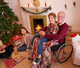 Image showing Family, christmas and love of child, grandpa and mother together to open gift or present together at fireplace in home living room. Senior man in wheelchair with boy and woman to celebrate holiday