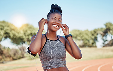 Image showing Running, portrait of woman on track with headphones and phone for fitness app on happy workout. Technology, sports and black woman runner with smile streaming music on run for health and wellness.