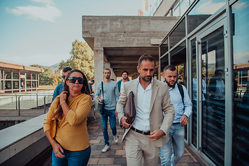 Image showing A diverse group of businessmen and colleagues walking together by their workplace, showcasing collaboration and teamwork in the company.