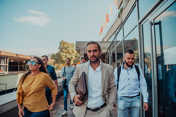 Image showing A diverse group of businessmen and colleagues walking together by their workplace, showcasing collaboration and teamwork in the company.