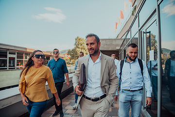 Image showing A diverse group of businessmen and colleagues walking together by their workplace, showcasing collaboration and teamwork in the company.