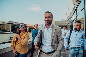 Image showing A diverse group of businessmen and colleagues walking together by their workplace, showcasing collaboration and teamwork in the company.