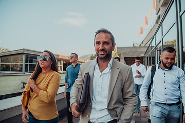 Image showing A diverse group of businessmen and colleagues walking together by their workplace, showcasing collaboration and teamwork in the company.